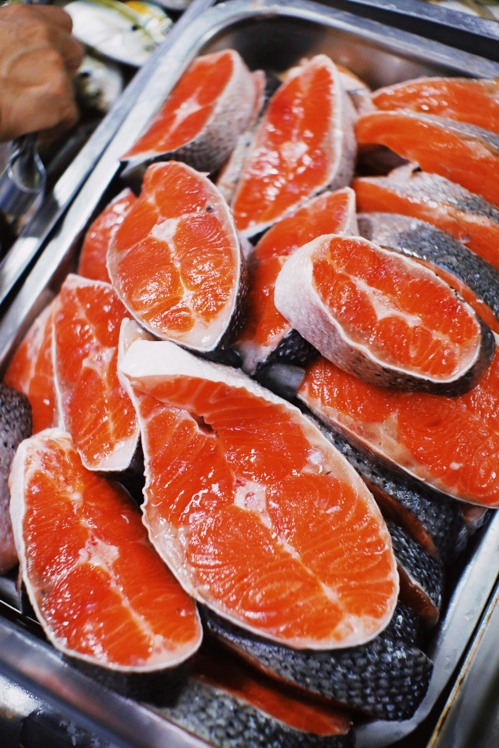 From above of fresh raw steaks of red salmon placed in heap in metal container in local market